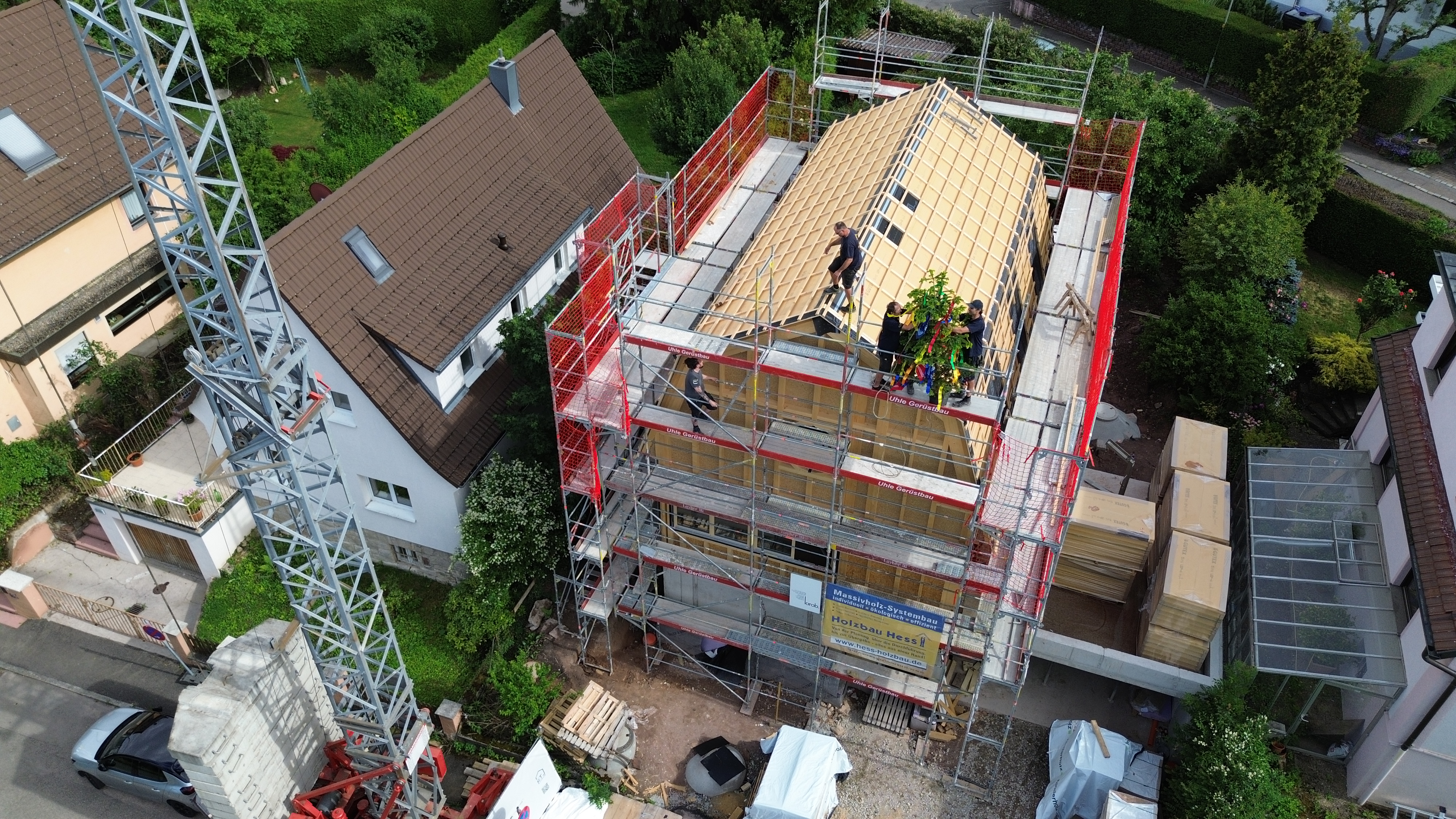 Ökologischer Holzbau Stuttgart – Luftaufnahme des Rohbaus mit Gerüst und Richtfestbaum